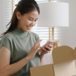 A happy customer unboxing their products and capturing the moment with their mobile device.