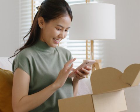 A happy customer unboxing their products and capturing the moment with their mobile device.