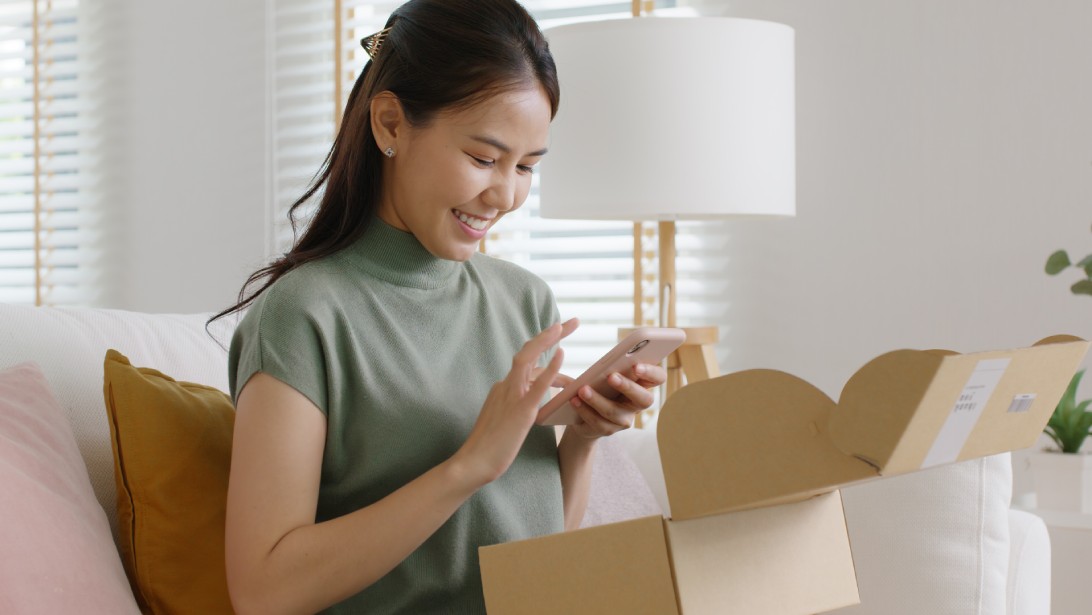 A happy customer unboxing their products and capturing the moment with their mobile device.