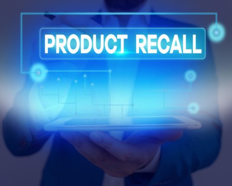 A man holds a tablet that has a blue light shining from it and the words "Product Recall" above it.